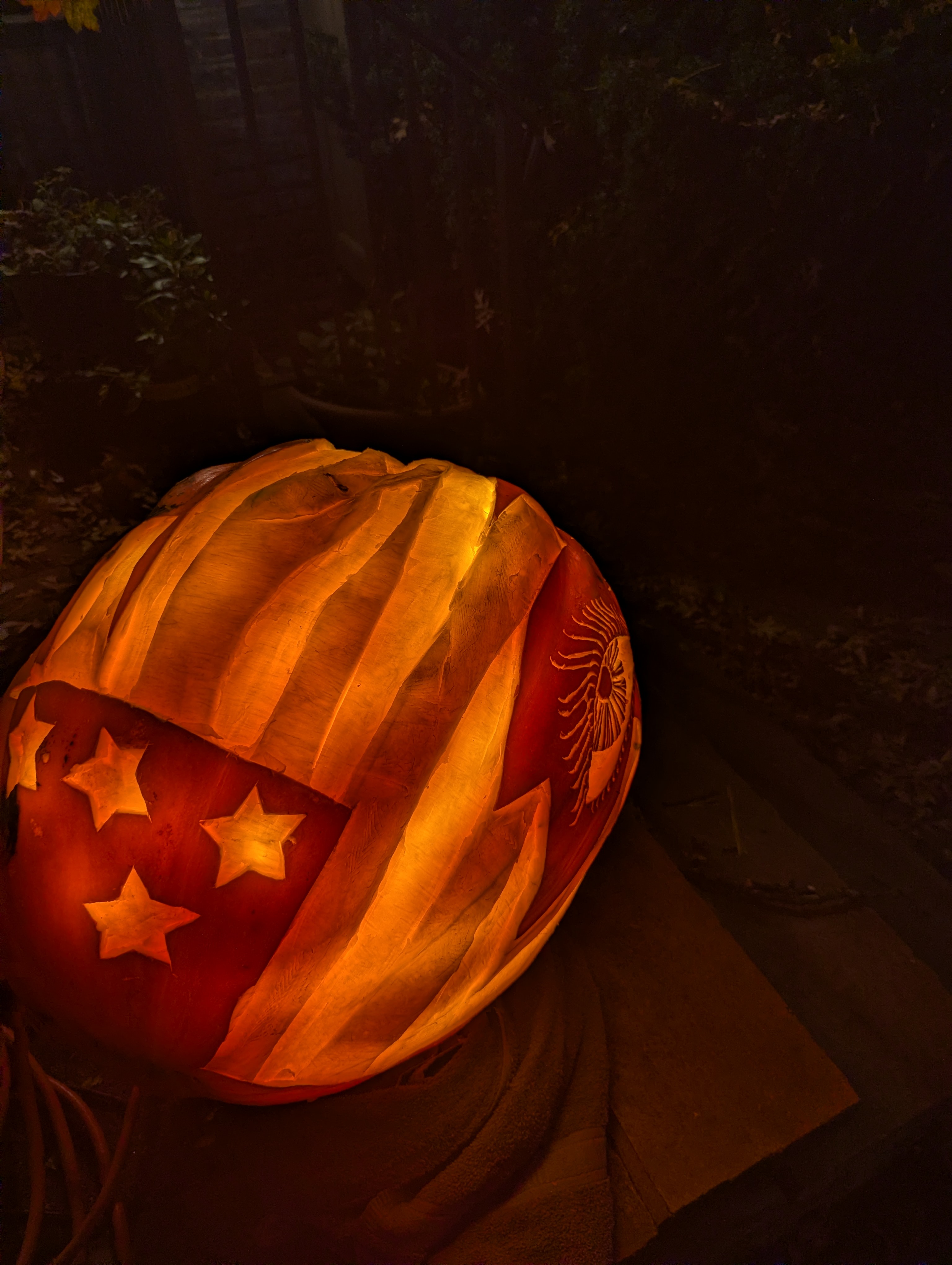 Same pumpkin from a second angle, showing the tattered flag fibers and the carving as a hug.